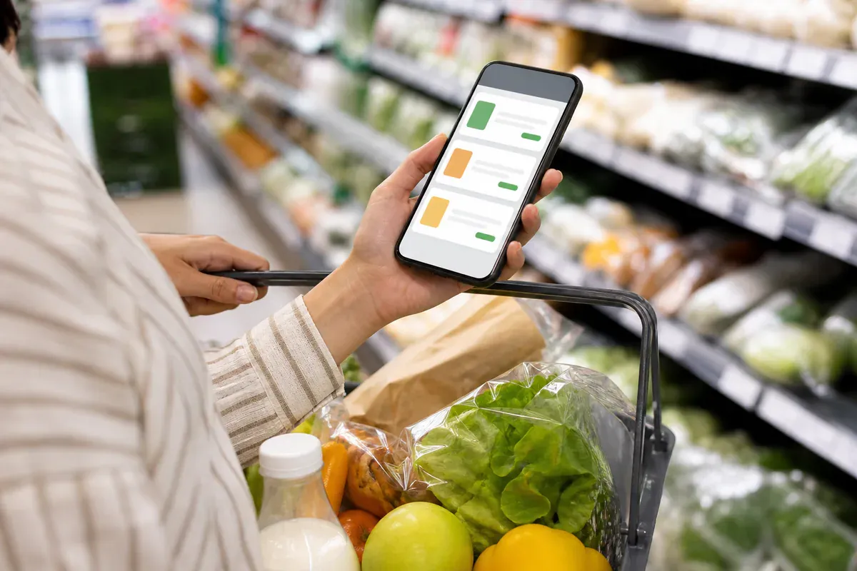 Markasız market ürünleri yanında telefondan fiyat karşılaştıran bir alışverişçi